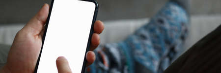 Close-up of male hands holding modern smartphone. Guy flipping news on cellphone or chatting with friends. Copy space on blank screen of phone. Electronic devices conceptの写真素材