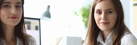 Portrait of gorgeous woman sitting at modern workplace and looking at camera with gladness. Joyful lady holding paper tablet with important biz documents. Accounting office conceptの写真素材