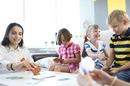 Children play board game with cards with mom. Teaching children through educational games conceptの写真素材
