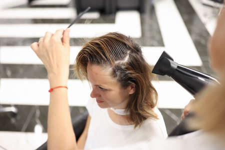 For woman in hairdressing salon master blow-dry her hair and styled her hair. Beauty salon services...