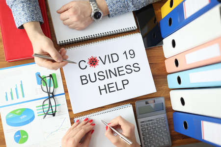 Man and woman are holding ballpoint pens over document covid 19 business help top view. Planning for way out of economic crisis after pandemic concept.の写真素材