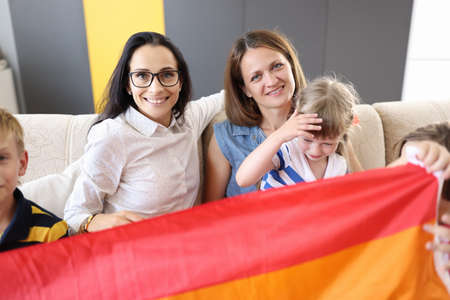 Two women and children hold lgbt flag. Same-sex marriage and children in it conceptの写真素材