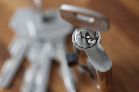 Steel key in keyhole lying on wooden table closeup. Reliable property protection concept.の写真素材