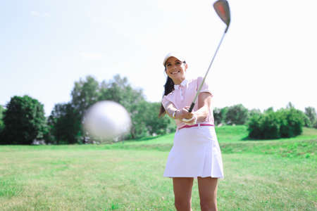 Woman golfer makes a hit with a club on ball. Golf game and everyday hobby conceptの写真素材