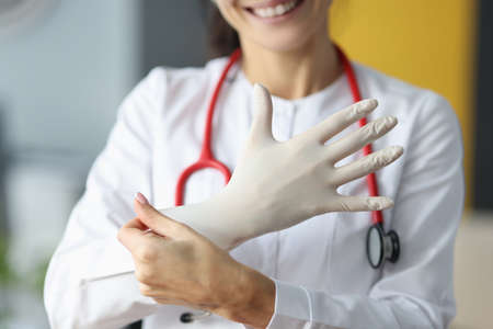 Smiling doctor puts on a white glove. Sterility in a medical facility conceptの写真素材