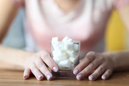 Female hands hold glass with sugar. Sugar addiction how to get rid of conceptの写真素材