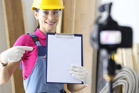 Woman builder writes down advice on repair of apartments and houses to camera. Calculation of...