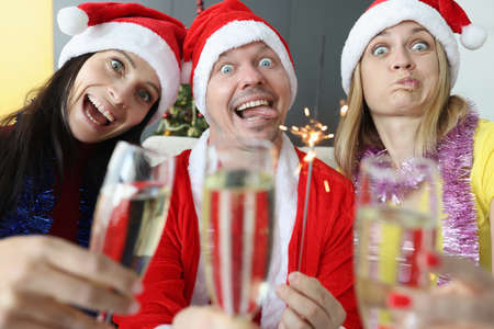 Man and two women rejoice and celebrate Christmas. New Year holidays and corporate parties conceptの写真素材