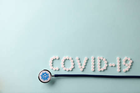 On the table is a stethoscope and an inscription from covid-19 tablets. Coronavirus infection and...