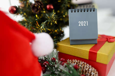Paper calendar and new years gift standing near Christmas tree at home. Planning for the next year...