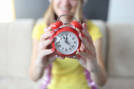 Woman holding red alarm clock in her hands on new years eve closeup. Time for everything by christmas conceptの写真素材