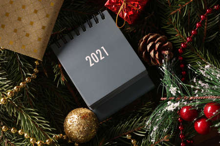 Desk calendar for 2021 lying on table among Christmas tree decorations closeup. Scheduling meetings for next year conceptの写真素材