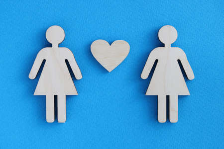Wooden women between them heart on blue background. Relationship between women conceptの写真素材