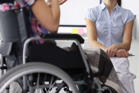 Woman in a wheelchair in consultation with psychologist. Psychological assistance to people with disabilities conceptの写真素材