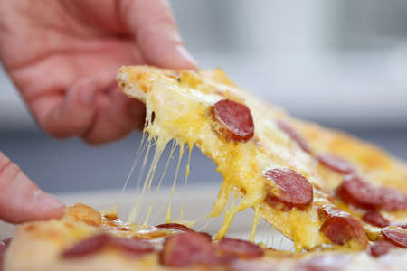 Mans hand holds a slice of pizza. Fast pizza delivery conceptの写真素材