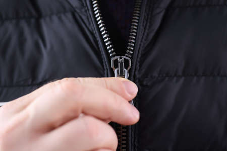 Male hand closing zipper on black jacket closeup. Custom tailoring conceptの写真素材