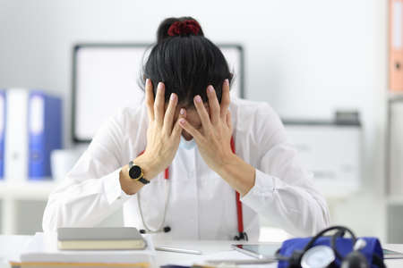Tired doctor bowing his head in office after a working day. Stressful situations in the medical...