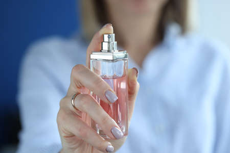 Glass container with perfume is in womens hands. Womens perfume and its types concept