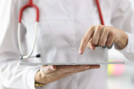 Doctor holding tablet in his hands and pointing at it with his finger closeup. Remote patient counseling conceptの写真素材