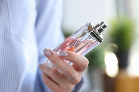 Woman holding bottle of perfume in her hands closeup. Aromatherapy concept