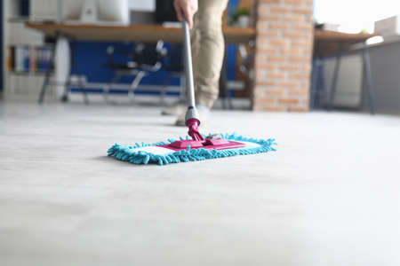 Professional cleaning services for complex cleaning of premises. Man wash floor Mop with damp cloth indoors.の写真素材