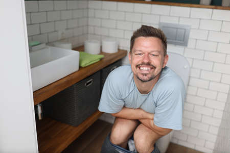 Man with emotion of relief sit on toilet with diarkey. Professional treatment for indigestion and constipation.の写真素材