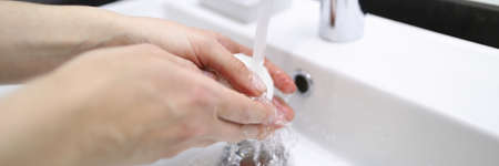 Man thoroughly washes his hands with soap under tap. Disposable hand disinfection during pandemic....
