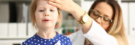 Professional pediatrician being at work while checking temperature of her little patientの写真素材