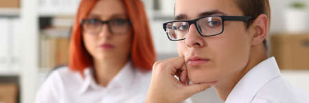 Serious project manager leaning elbow on the table and touching chin, waiting for the beginning of meetingの写真素材