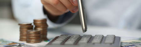 Professional financier uses calculator to count his incomes, sitting at his workplace