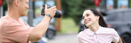 Male photographer with camera photographs smiling woman. Professional services photographer conceptの写真素材