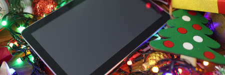 On table is tablet and New Years decorations. Choosing gift for the New Year concept