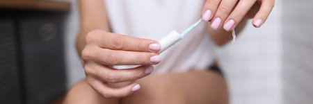Woman sitting on toilet and holding a hygienic tampon in her hands Menstruation in women conceptの写真素材