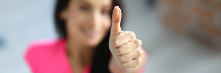 Woman in sportswear smiles and holds her thumbs up. Sport and a positive start to the day concept