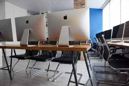 Minsk, Belarus - 30 July 2020: Many silver monitors for business people standing on wooden table in empty office closeup. Illustrative editorialのeditorial素材