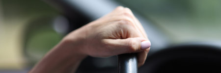 Female hand hold leather steering wheel in car. Driving training.の写真素材