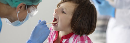 Little girls throat is examined at doctors appointment. Medical care for children and health...