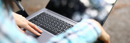 Woman wheelchair kneeling stands laptop. Remote work disabled conceptの写真素材