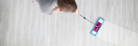 Man washes floor with mop on light floor. Helping husband with housework conceptの写真素材