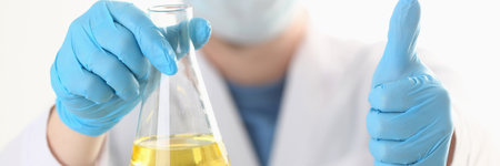 Close up of male hands in sterile gloves holding vaccine and showing approval gestureの写真素材