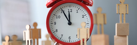 There wooden little men around red alarm clock. Time management in business concept