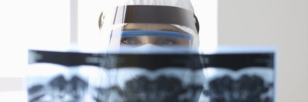 Doctor in protective suit is looking at an X-ray image. Medical diagnosis concept