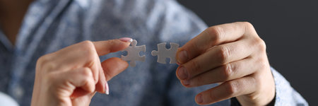 Mans and a womans hand connecting two puzzle pieces closeup. Resolution of family conflicts conceptの写真素材