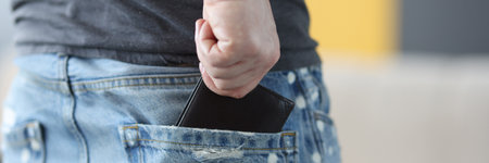 Man pulling out wallet from back pocket of jeans closeup. Keeping money concept