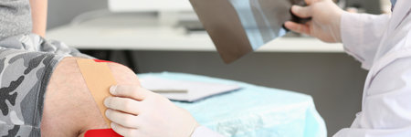 Cropped head of doctor looking at photo of patient injured knee for diagnosis and treatment