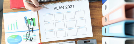 Male and female hands holding ballpoint pen with documents with plan for 2021 at table in office....