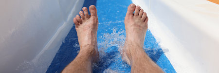 Male feet on background of roller coaster in the water park closeup. Safety rules for water attractions concept.の写真素材