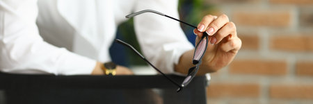 Business woman in a white blouse holds glasses for vision. Woman heads the departmentの写真素材