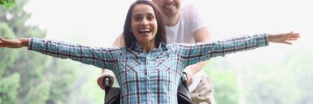 A guy and a woman in a wheelchair are walking in the summer forest. A disabled woman is happy with a healthy manの写真素材
