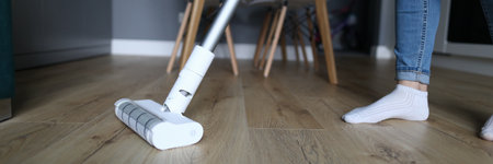 A woman in jeans and socks stands on a laminate in an apartment and washes the floor. Housewife wipes the floor covering at homeの写真素材